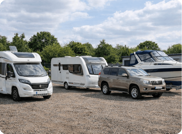 Motorhome, caravan, four-wheel drive and boat parked in outdoor storage area